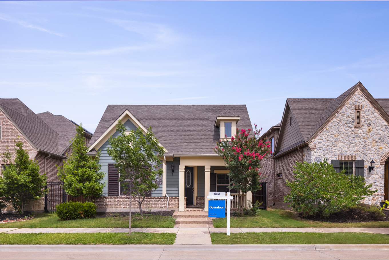 A modern single-family home with a manicured front lawn on a quiet residential street.