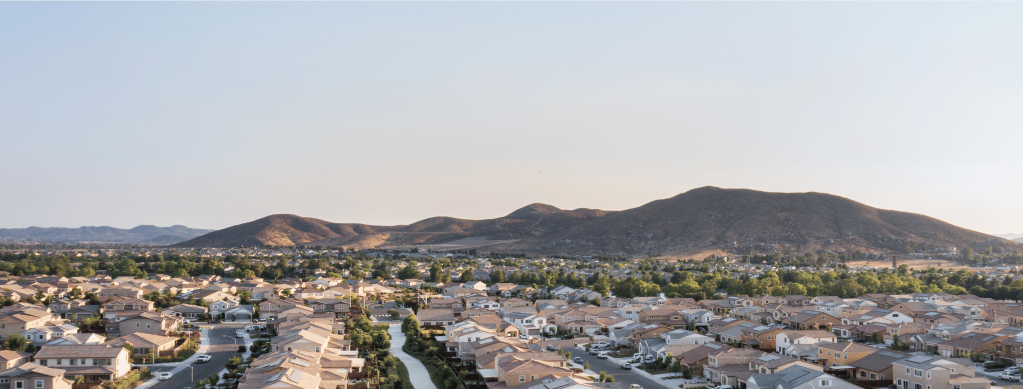 A wide-angle view of a suburban neighborhood with tree-lined streets and single-family homes