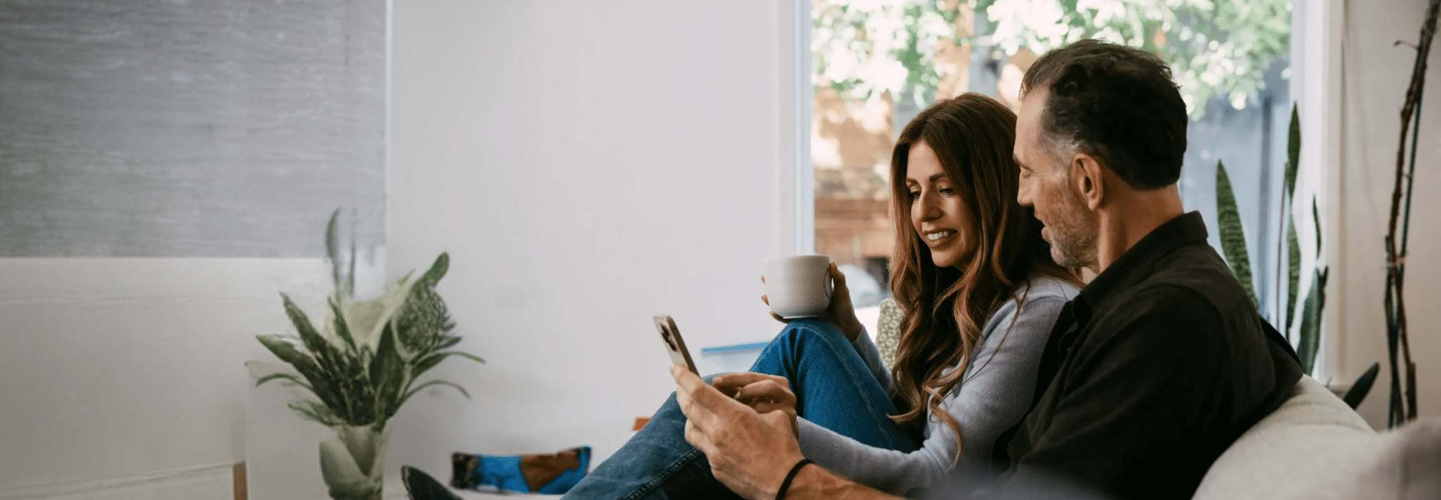 Couple sitting on a sofa in a living room looking at a smartphone together