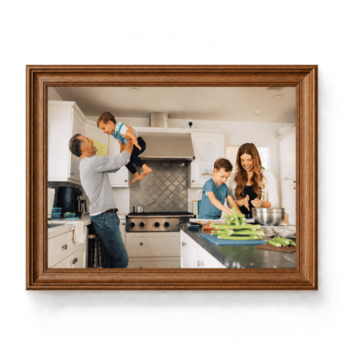 A family in a kitchen, shown in a wooden frame